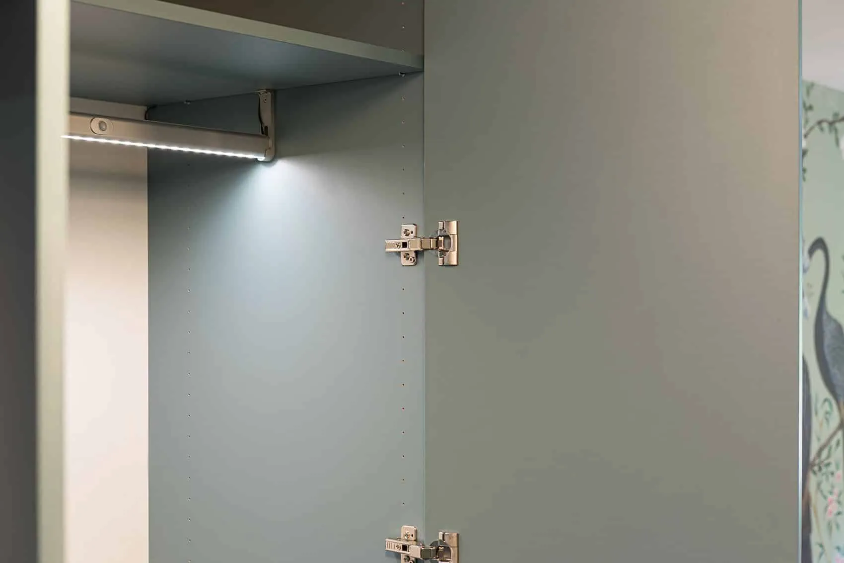 Intérieur de placard gris-vert avec barre d’éclairage LED, rangements sur mesure de l’appartement Gillet