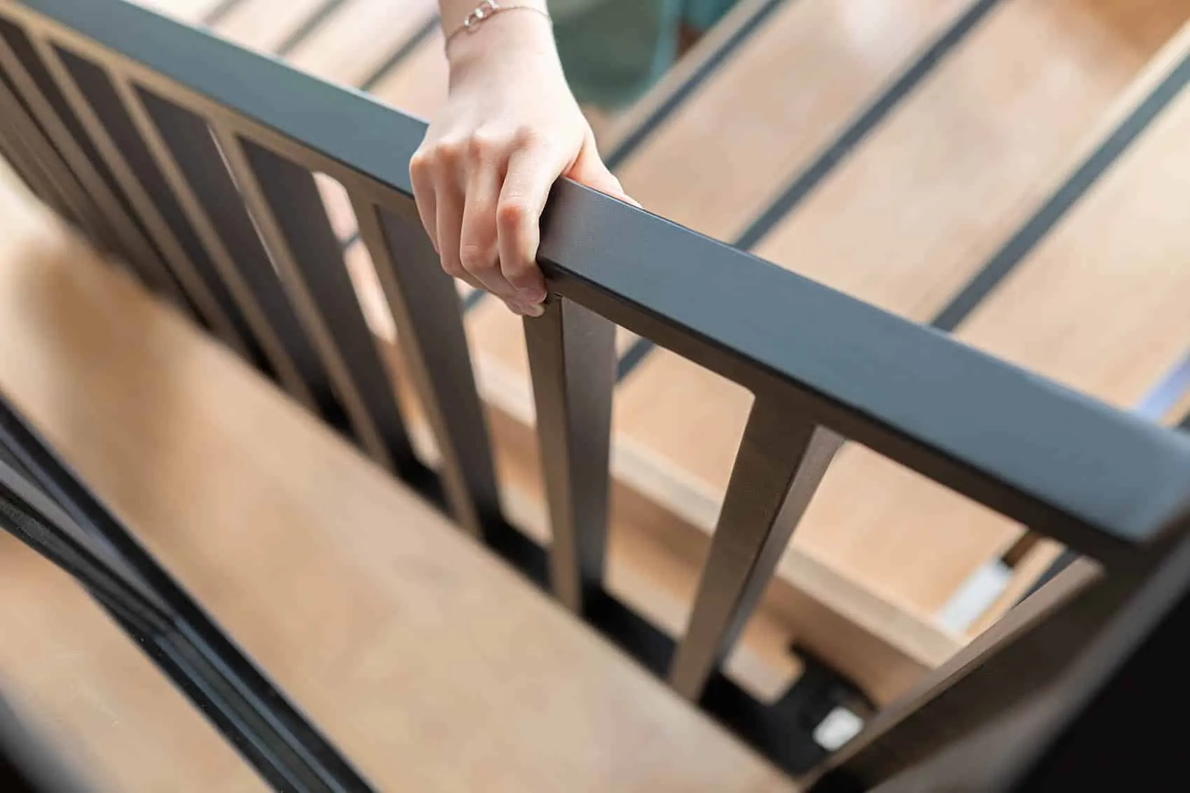 Main sur la rampe en métal noir de l’escalier menant à la mezzanine du restaurant Le Dérobé