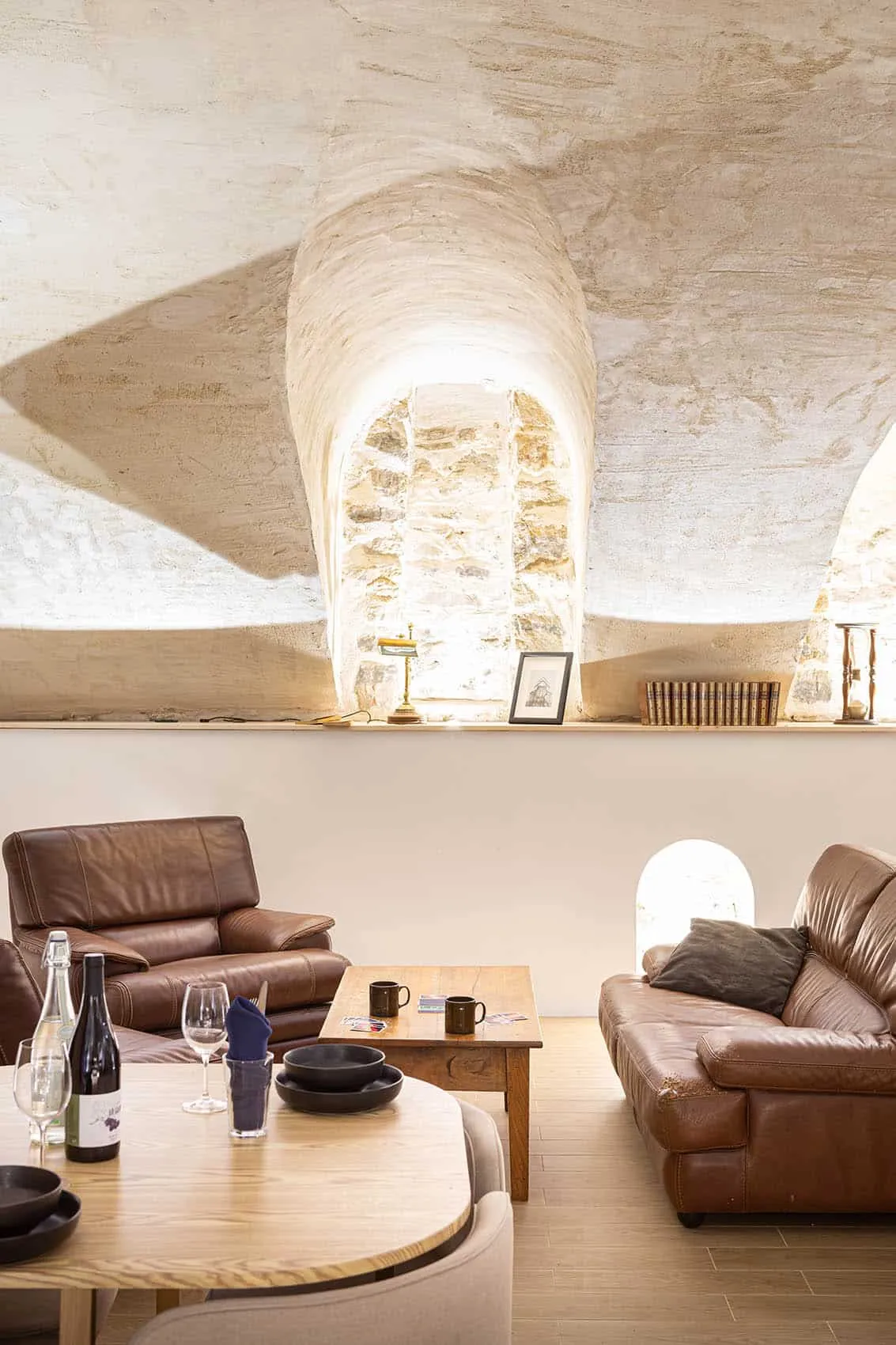Niche voûtée en pierre apparente éclairée au-dessus des fauteuils en cuir, patrimoine canut mis en valeur