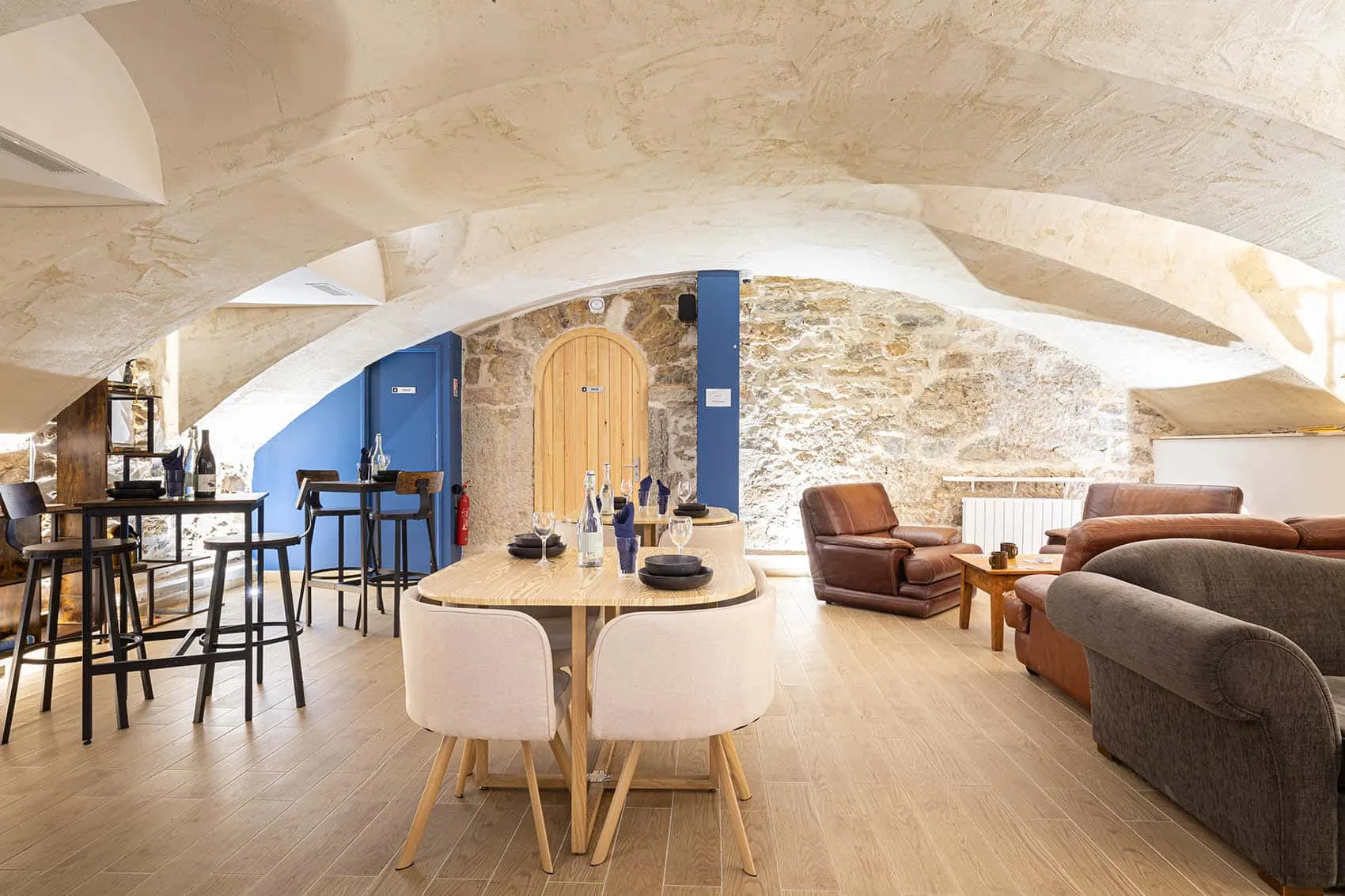 Salon sous la cave voûtée du restaurant Le Dérobé à Lyon, fauteuils en cuir et murs en pierre
