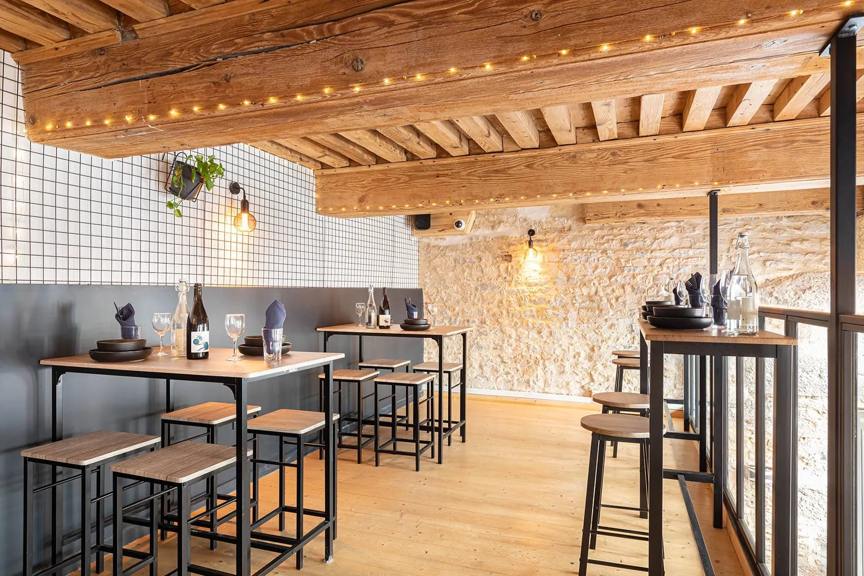 Salle du restaurant Le Dérobé à la Croix-Rousse, plafond à poutres, murs en pierre et tables hautes, aménagée par Picture Design