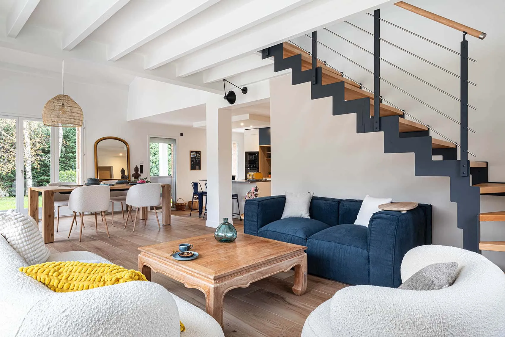 Séjour lumineux de la Maison Noyer : canapés bleu et blanc, poutres blanches et escalier métallique, rénovation par Picture Design