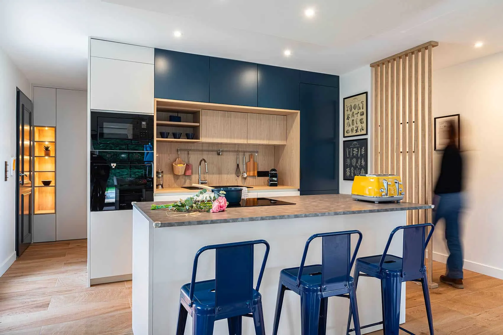 Cuisine bleue sur mesure avec îlot central, tabourets bleus et claustra en bois, conçue par un architecte d'intérieur à Lyon
