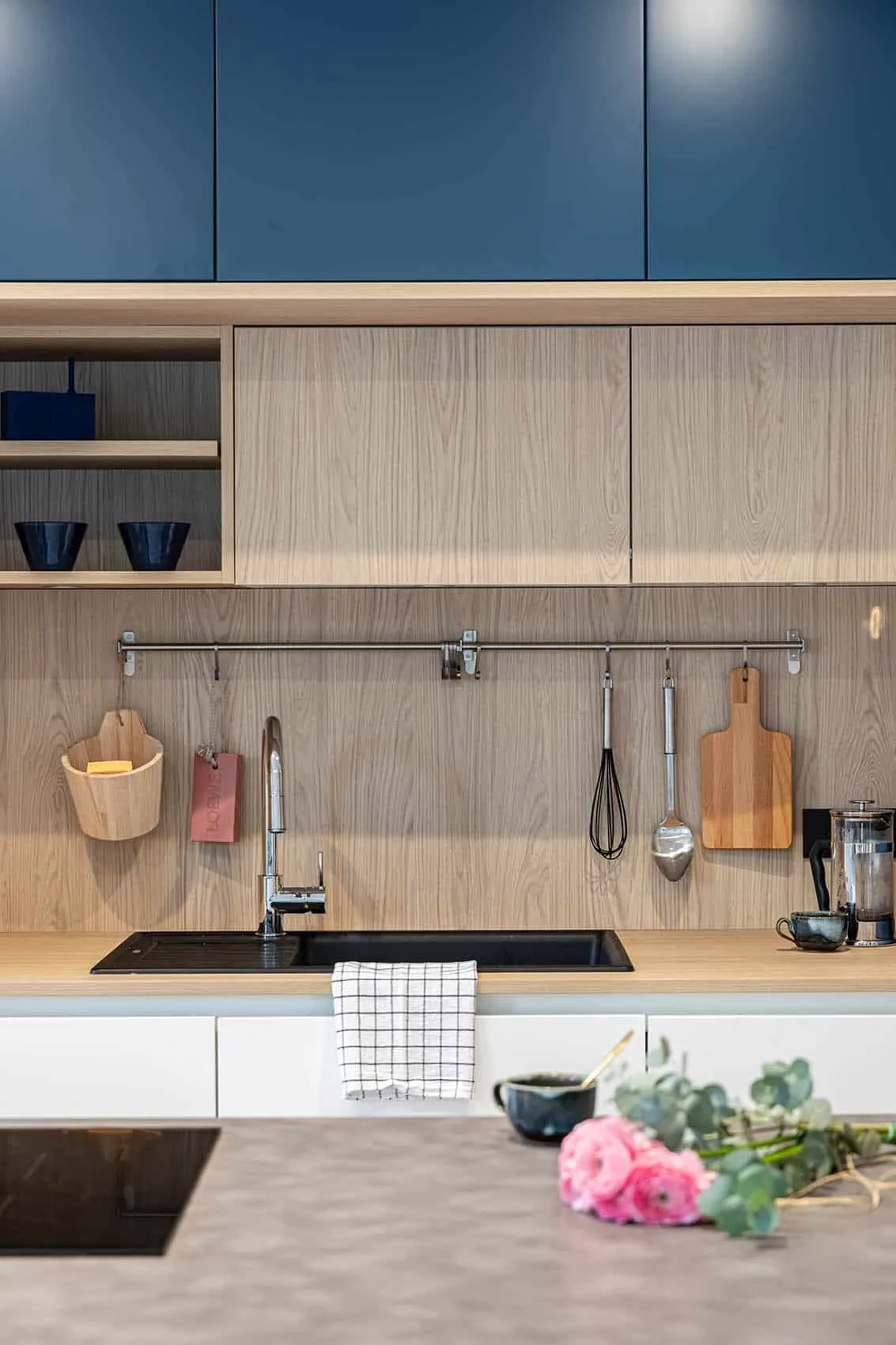 Détail de la cuisine : crédence et étagères en bois, façades bleues et plan de travail en pierre