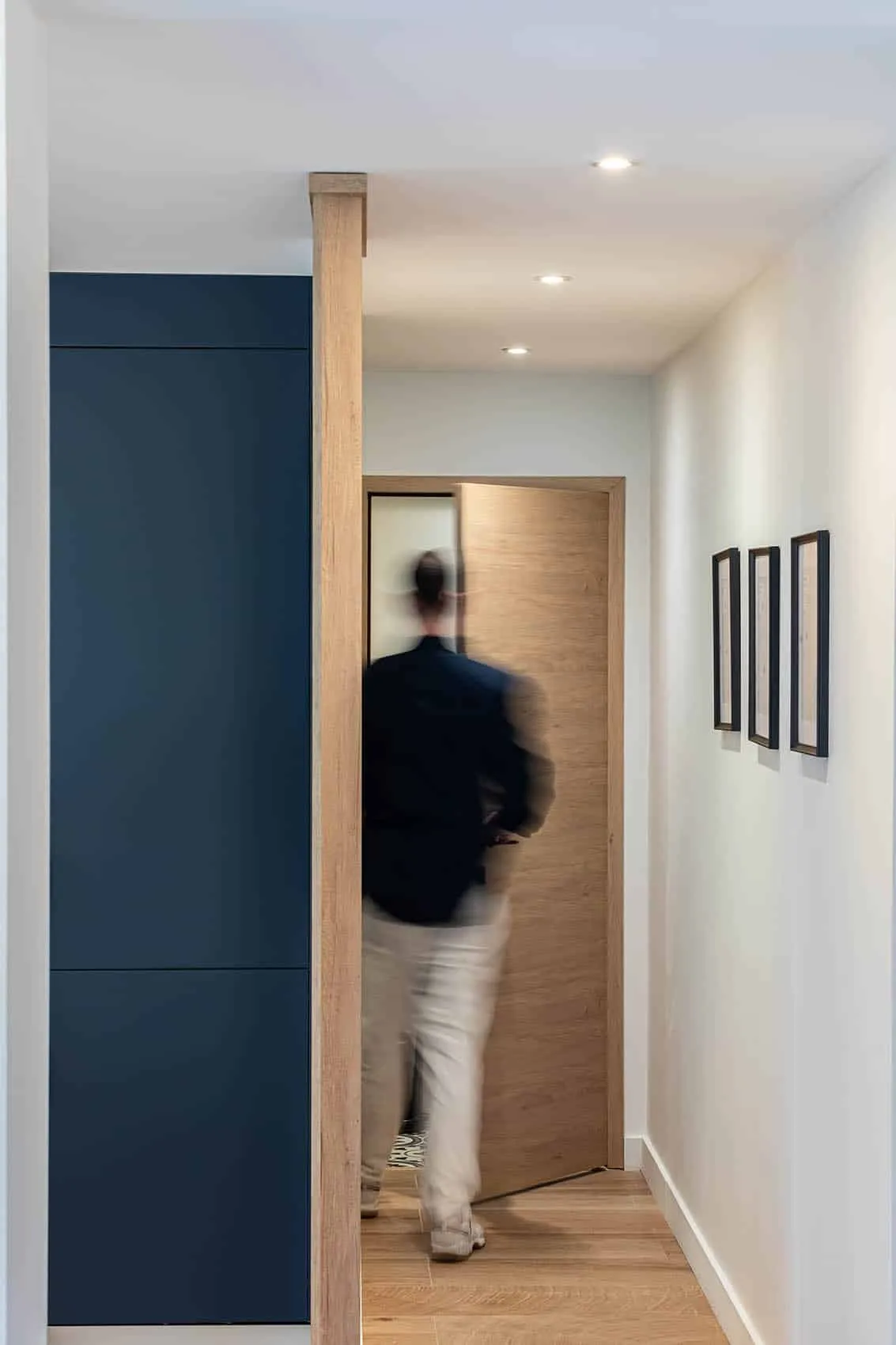 Dégagement aux portes en bois et placard bleu nuit, circulation repensée dans une maison rénovée