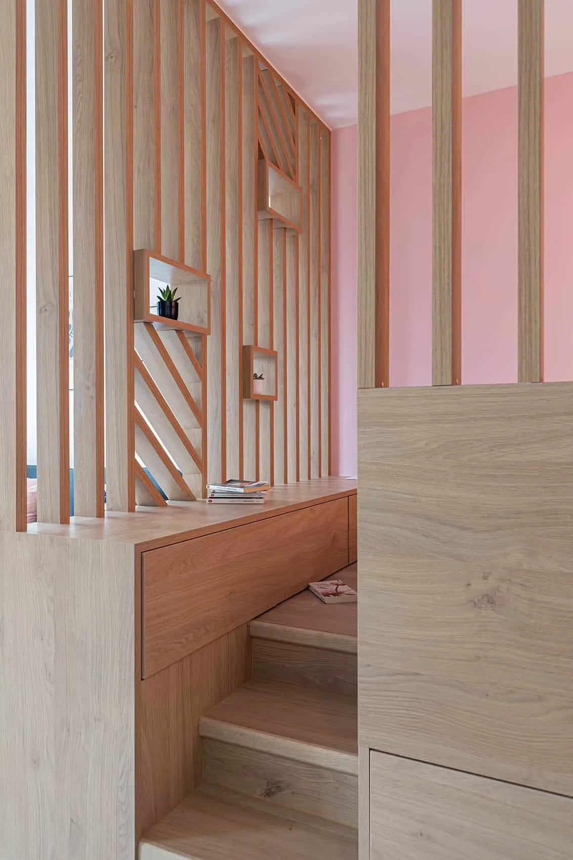 Marches et rangements sur mesure en bois intégrés au coin nuit d’un studio