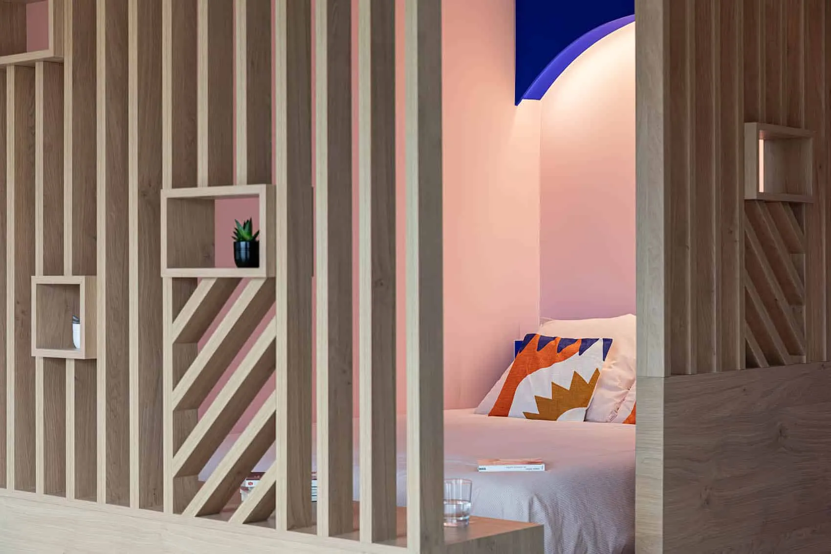 Claustra en bois à motifs et niches ouvertes devant le coin nuit