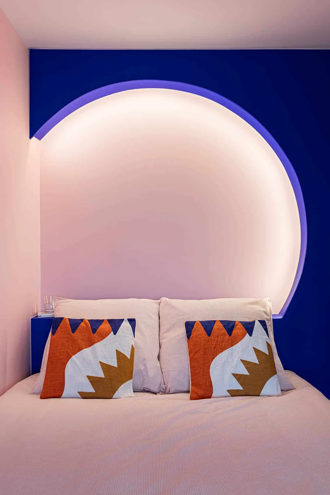 Tête de lit ronde rétroéclairée par un bandeau LED dans une alcôve bleu Klein
