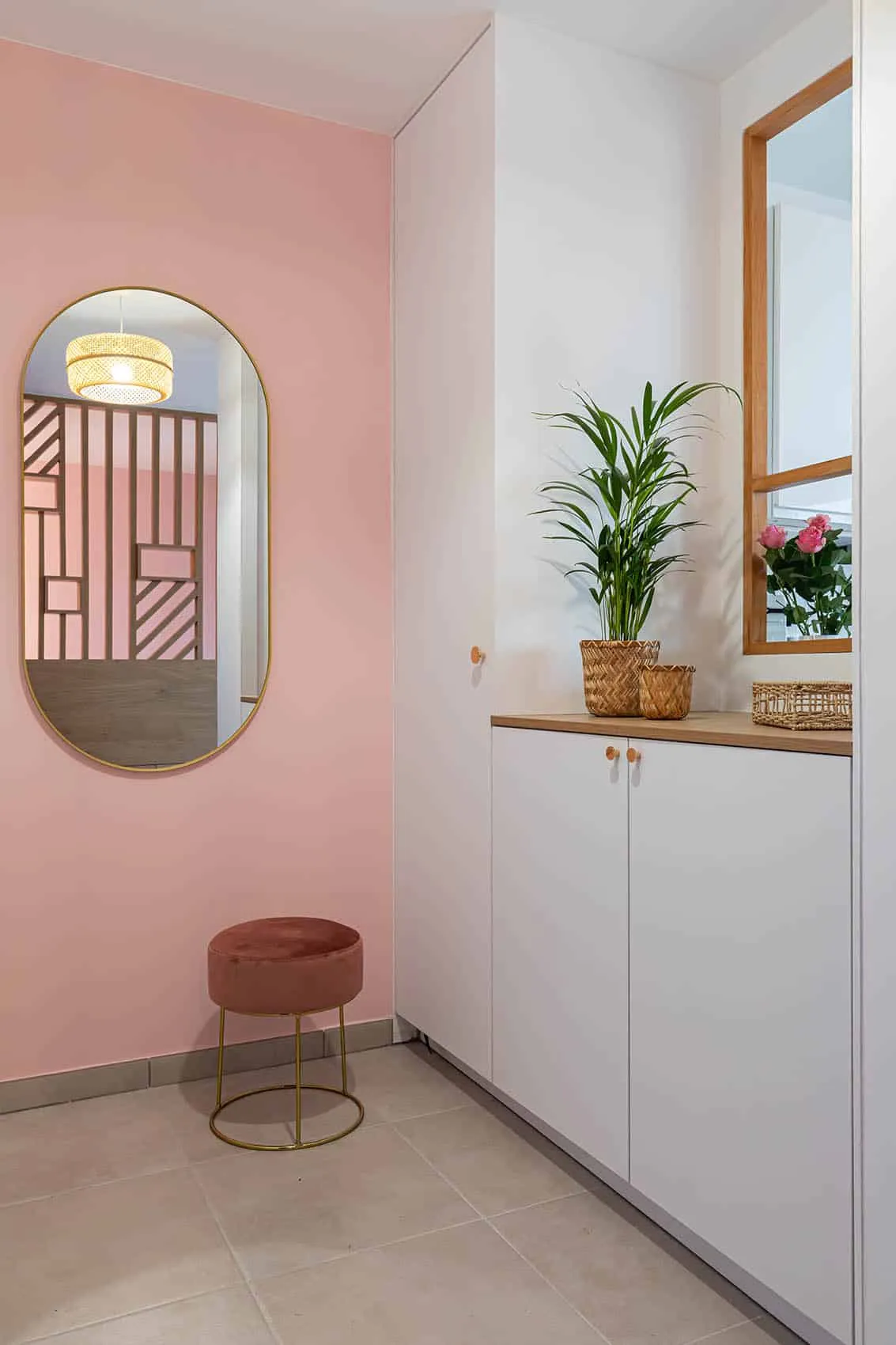 Entrée rose poudré avec miroir ovale et rangements blancs