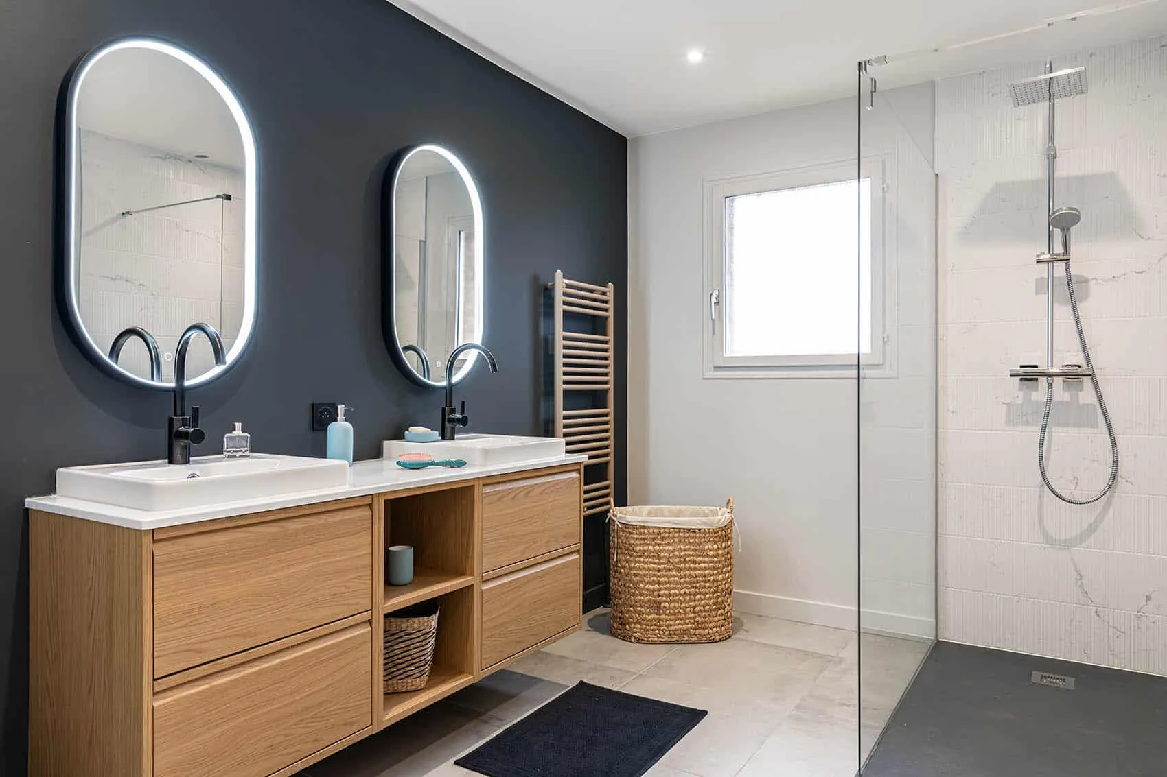 Salle d'eau avec double vasque sur meuble en bois, miroirs ovales lumineux et douche à l'italienne, rénovation de salle de bains