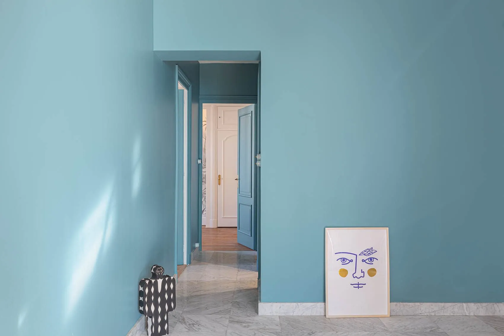 Entrée peinte en bleu clair Grey Stone de Little Greene, sol gris et affiche à visage posée au sol