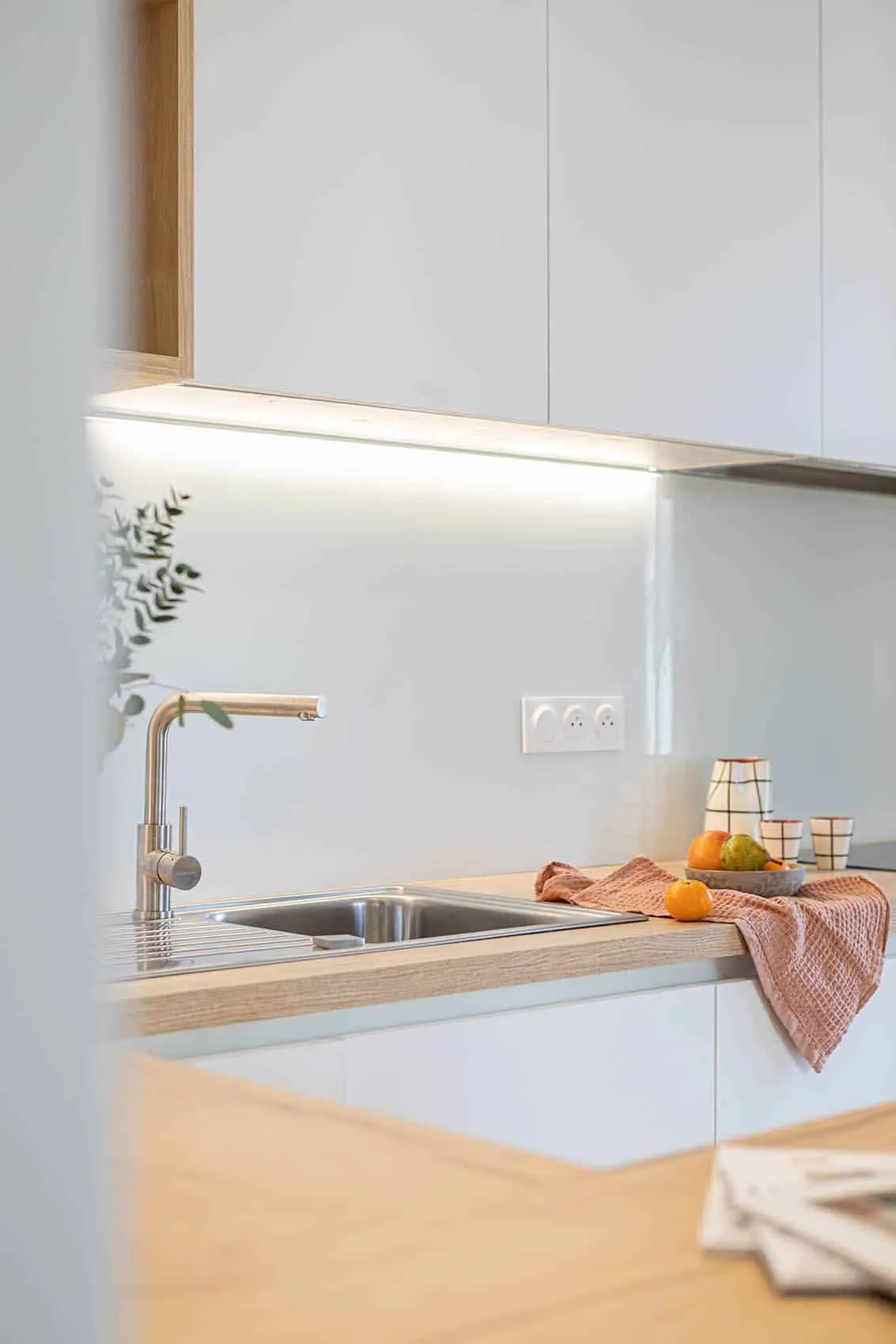 Évier inox à double bac et mitigeur sous éclairage LED, crédence blanche de la cuisine Garibaldi