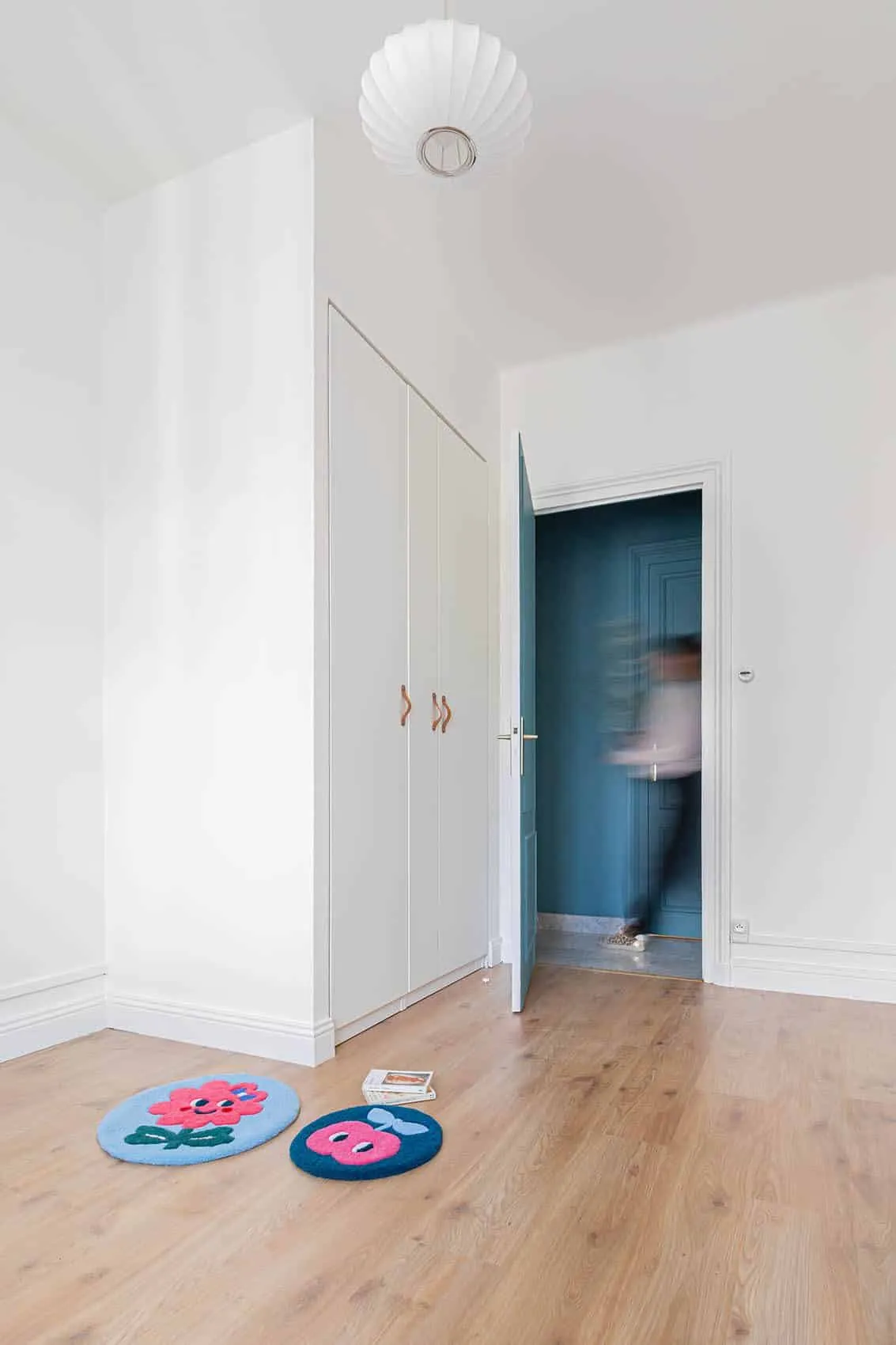 Placards blancs intégrés à poignées en cuir près d’une porte bleue, couloir de l’appartement Garibaldi