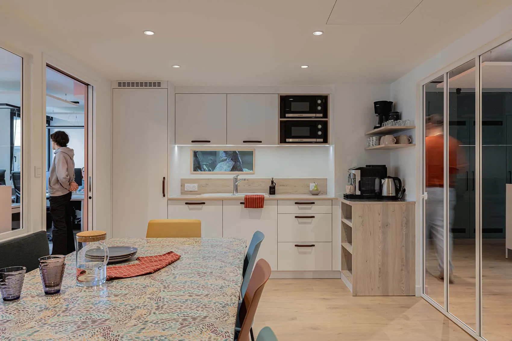 Kitchenette moderne intégrée à des bureaux professionnels à Lyon, avec mobilier sur mesure, espace café et coin repas convivial.