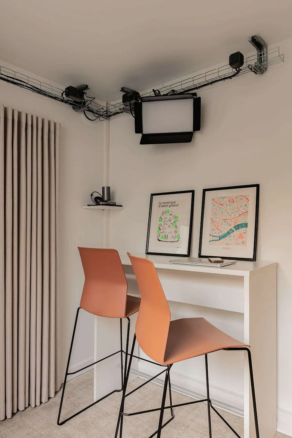 Coin bar avec tabourets orange et affiches encadrées, espace convivial de bureaux à Lyon