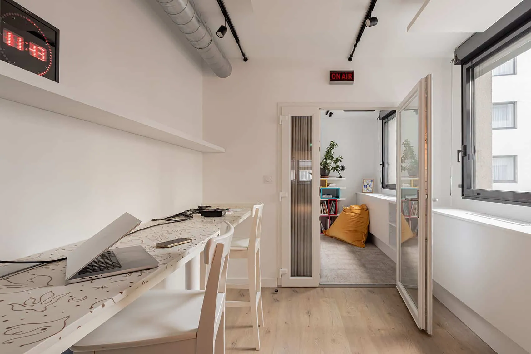 Salle de travail avec plan de travail blanc, tabourets et porte vitrée, bureaux rénovés à Lyon