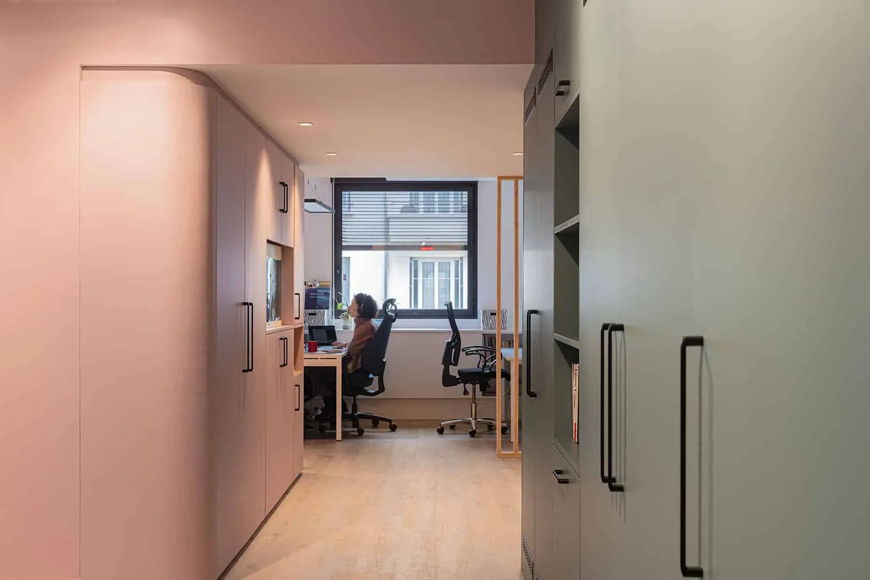Bureau fermé vu depuis un couloir aux placards rose et vert sauge, architecte d'intérieur pour les entreprises à Lyon
