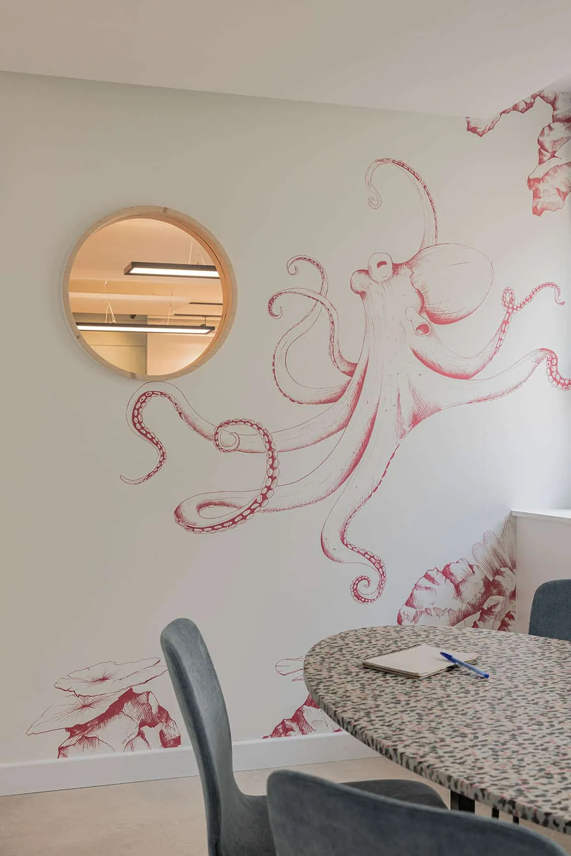 Mur peint d'une pieuvre rose et miroir hublot dans un bureau, aménagement de bureaux à Lyon
