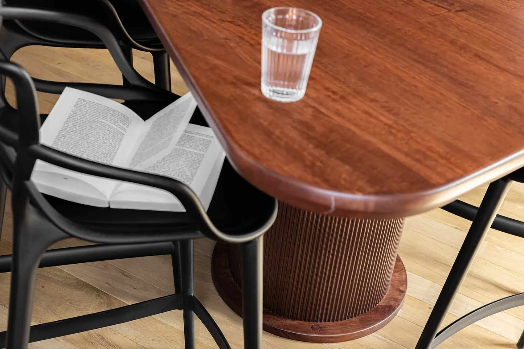 Détail de décoration : table en bois aux bords arrondis, livre ouvert et verre d'eau, appartement de la Croix-Rousse rénové par Picture Design à Lyon