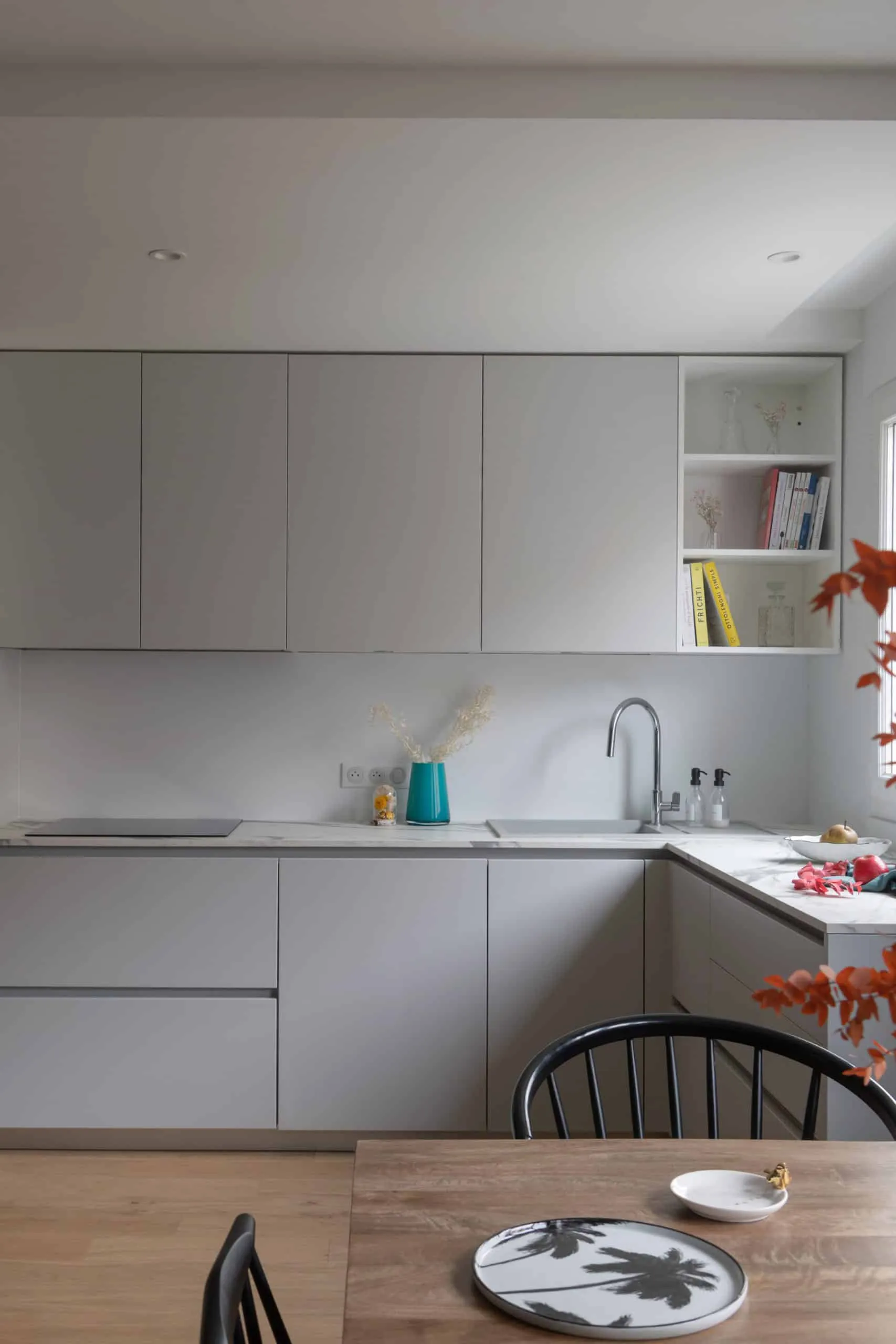 Plan de travail effet marbre, évier et façades gris clair dans la cuisine épurée de l’appartement Bugeaud