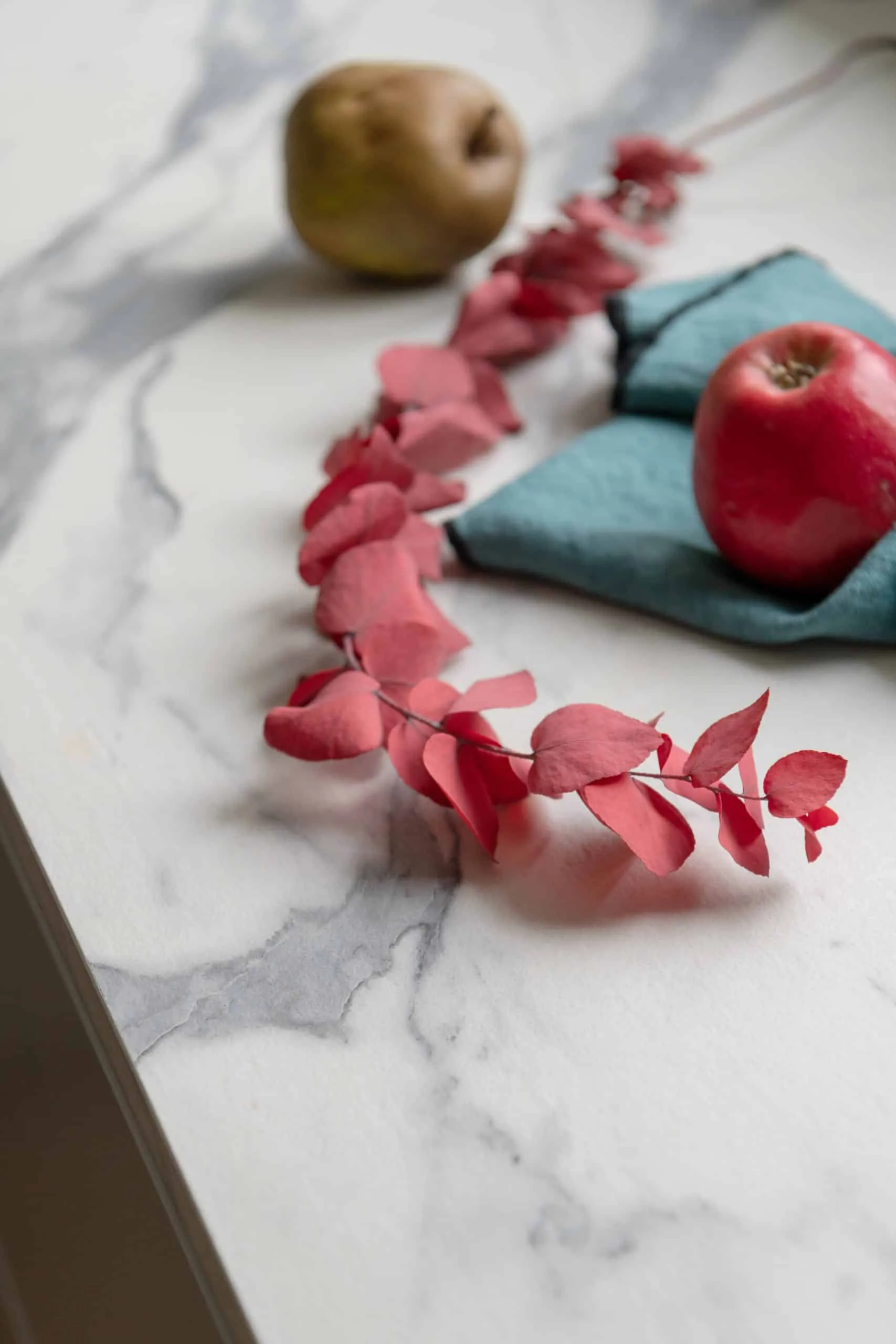Détail du plan de travail effet marbre blanc avec feuillage séché rose et grenade, cuisine au design épuré
