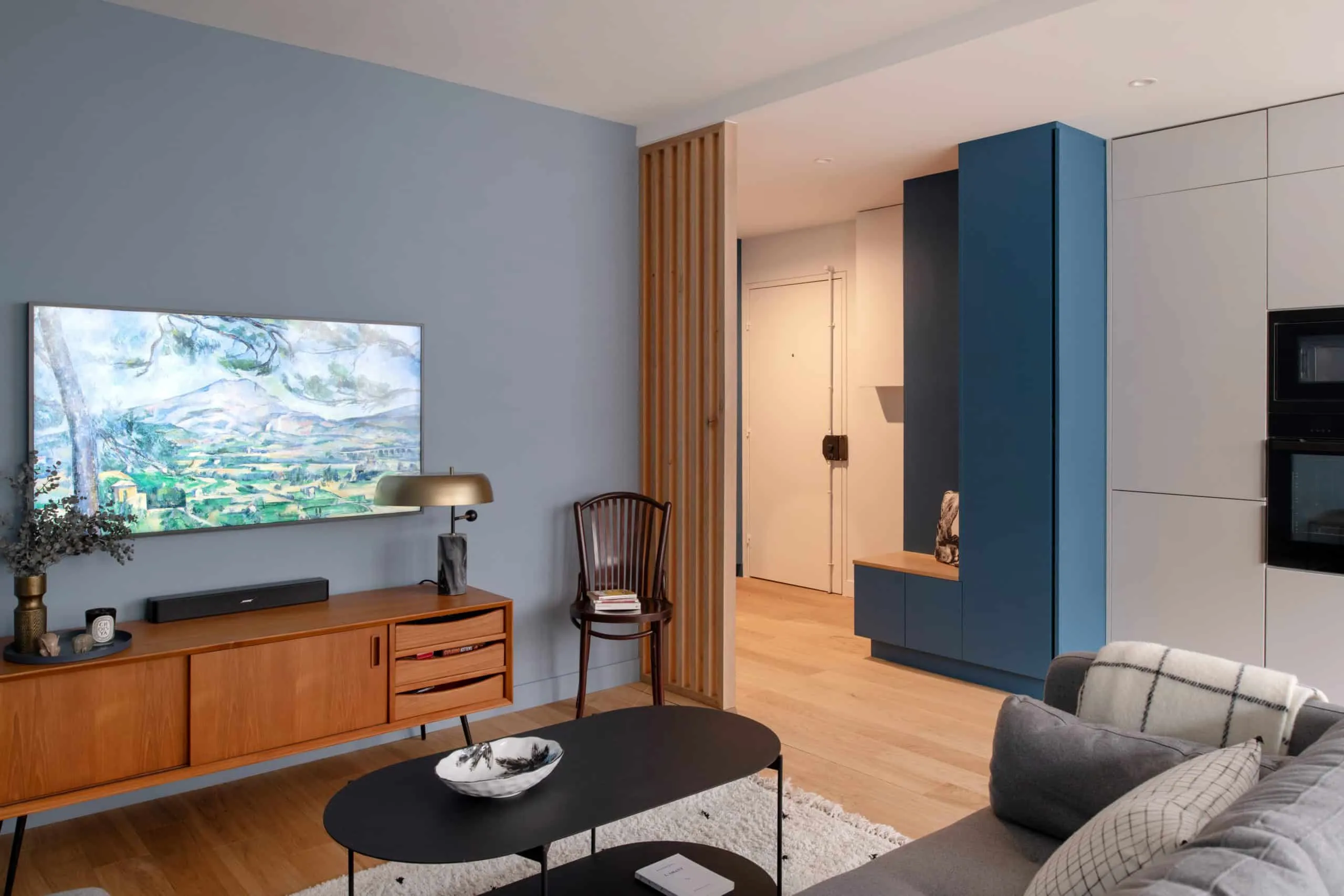 Séjour vintage et scandinave avec chaise bistrot, lampe en laiton et meuble bleu dessiné sur mesure près de l’entrée