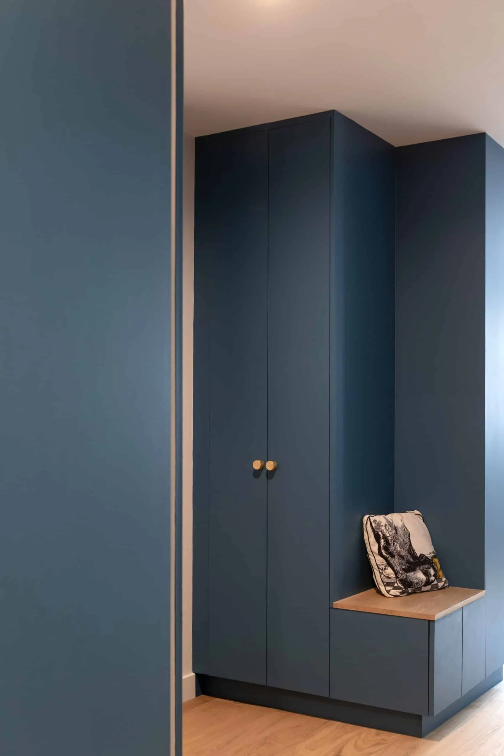 Placards sur mesure bleu profond aux boutons dorés dans l’entrée de l’appartement rénové à Lyon