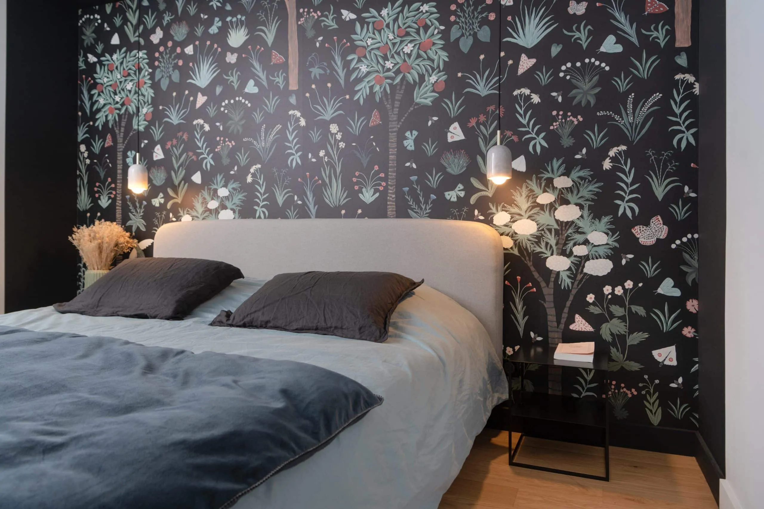 Chambre de l’appartement Bugeaud : papier peint botanique sombre, linge de lit bleu et gris, lampes de chevet