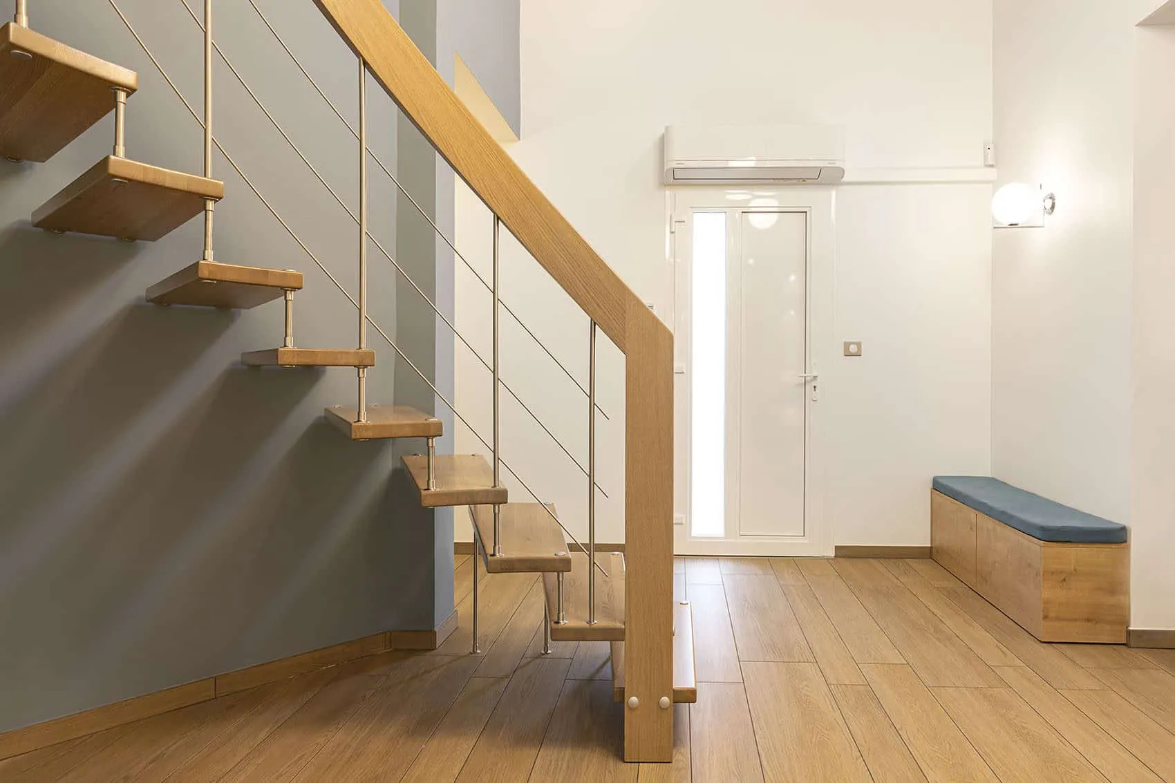 Entrée de la maison Villette : escalier aux marches en bois, garde-corps à câbles et banc sur carrelage effet bois