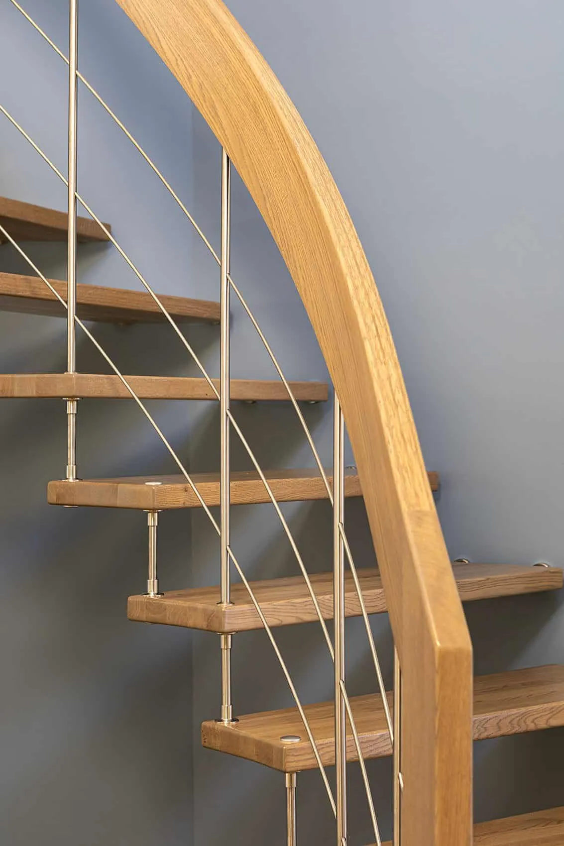 Marches en bois de l’escalier suspendu, câbles en inox et main courante porteuse en bois sur fond bleu