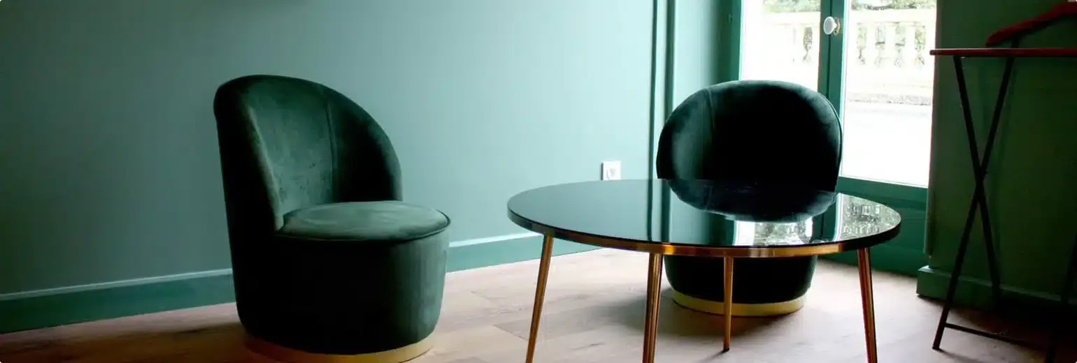 Fauteuils en velours vert et table basse en laiton devant une porte-fenêtre, décoration d’intérieur par Picture Design à Lyon