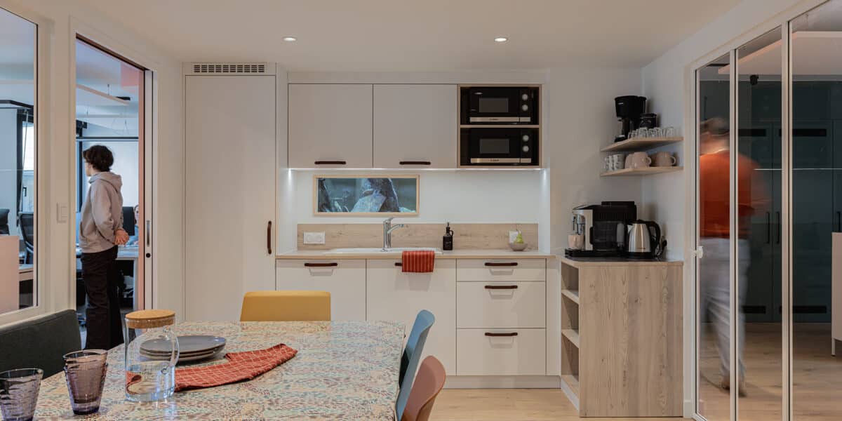 Kitchenette moderne intégrée à des bureaux professionnels à Lyon, avec mobilier sur mesure, espace café et coin repas convivial.