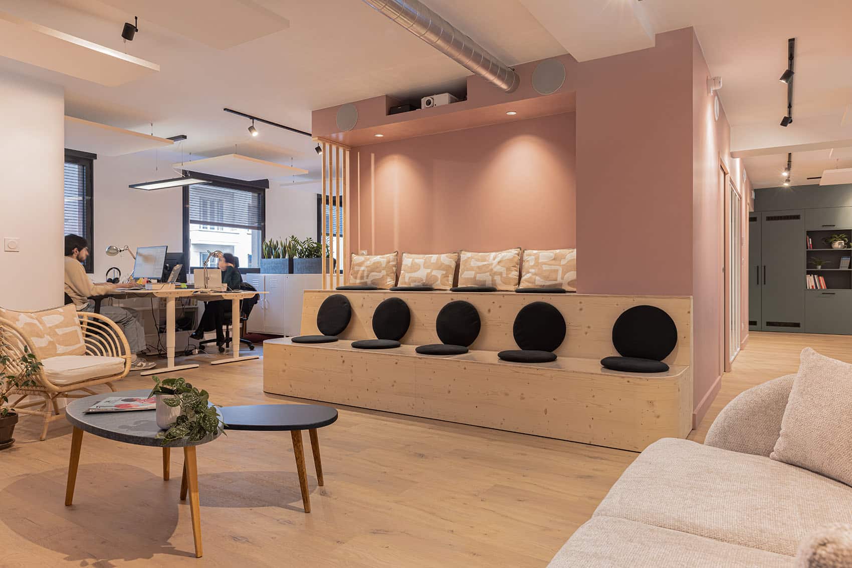 Espace de coworking contemporain conçu par un architecte d'intérieur à Lyon, avec assises en bois sur mesure, teintes poudrées et ambiance chaleureuse.