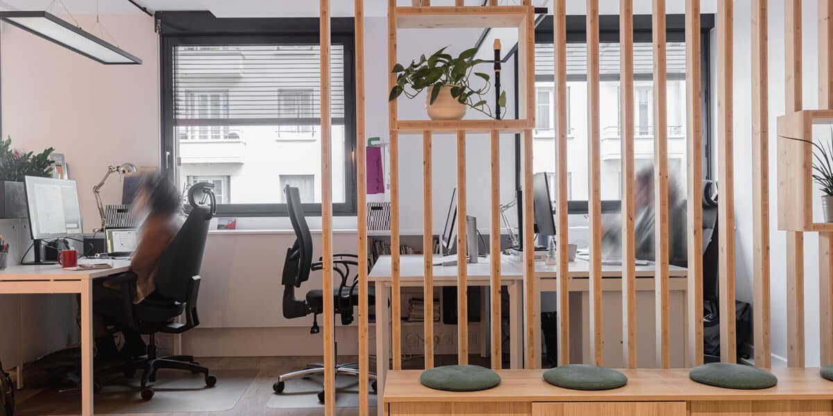 Cloison amovible à claire-voie en pin naturel séparant deux espaces de travail ouverts avec postes informatiques et rangements bois – bureaux Cap'Com à Lyon par Picture Design